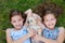 Twin sisters playing with chihuahua dog lying on lawn