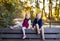 Twin toddler sibling boy and girl sitting on bench in autumn park.