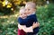 Twin toddler sibling boy and girl standing in autumn forest, hugging.