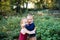Twin toddler sibling boy and girl standing in autumn forest, hugging.
