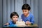 Twins adorable boy in blue shirt, celebrating his birthday, blowing candles on homemade baked cake, indoor. Birthday party for kid