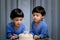 Twins adorable boy in blue shirt, celebrating his birthday, blowing candles on homemade baked cake, indoor. Birthday party for kid