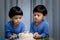 Twins adorable boy in blue shirt, celebrating his birthday, blowing candles on homemade baked cake, indoor. Birthday party for kid