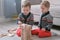 Twins boys brothers are building from wooden blocks sitting on the floor by the sofa in their room.