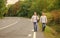 Twins walk along road. Brothers friends nature background. Long way. Adventure concept. Guys hitchhiking on road