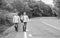 Twins walk along road. Brothers friends nature background. Long way. Adventure concept. Guys hitchhiking on road