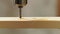 twist drill drills thru a wooden plank close-up in slo-mo