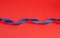 Twisted dark blue silk shiny ribbon on a red background