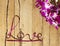 Twisted ribbon word Love with orchids on wood