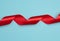 Twisted silk red ribbons for decoration on a blue background, top view