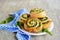 Twisted yeast buns stuffed with nettles, green onions and cheese on a white ceramic plate