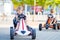 Two active little kid boys driving pedal race car in summer garden, outdoors.