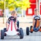 Two active little kid boys driving pedal race car in summer garden, outdoors. Children, best friends racing with fast