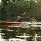 Two active male friends while boating together on a lake surrounded by peaceful nature