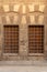 Two adjacent wooden closed windows with iron grid over decorated stone bricks wall, Medieval Cairo, Egypt