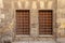 Two adjacent wooden windows with iron grid over decorated stone bricks wall, Medieval Cairo, Egypt