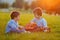 Two adorable boys, sitting on the grass, playing guitar