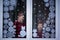 Two adorable brothers are looking through the window. There is decoration snowflakes from paper on the window