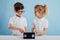 Two adorable childs with video tape, isolated on blue background