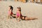 Two adorable fitness models wearing glasses and swimsuit practicing yoga together at the beach