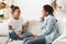 Two adorable girls sitting on sofa at home and talking