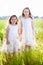 Two adorable girls in white dresses standing in the meadow