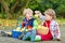 Two adorable little boy friends eating apples in home\'s garden,