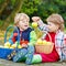 Two adorable little boy friends eating apples in home\'s garden,