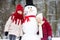 Two adorable little girls building a snowman together in beautiful winter park. Cute sisters playing in a snow.