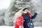 Two adorable little girls having fun together in beautiful winter park. Beautiful sisters playing in a snow.