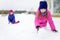 Two adorable little girls having fun together in beautiful winter park. Beautiful sisters playing in a snow.