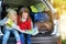 Two adorable little girls ready to go on vacations with their parents. Kids sitting in a car examining a map.