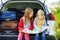 Two adorable little girls ready to go on vacations with their parents. Kids sitting in a car examining a map.