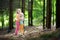 Two adorable little sisters hiking in a forest on summer