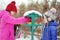 Two adorable sisters feeding birds on chilly winter day in city park. Children helping birds at winter.