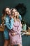 Two adorable women girlfriends in trendy hoodies hugging while posing in the decorated for Christmas interior