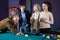 Two adult couples of different generations talk in the billiard
