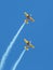 Two aerobatic aircraft perform a steep climb in deep blue sky