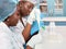 Two African scientists, technical assistants or graduates in lab coats and gloves perform PCR testing of patient samples in modern