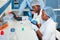 Two African scientists, technical assistants or graduates in lab coats and gloves perform PCR testing of patient samples in modern