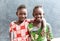 Two African Sisters Laughing and Smiling Outdoors with Toothy Smiles before School