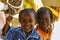 Two African unidentified kids, 4 to 6 years old, smiling laughing at outdoor school in tribal village near Saly