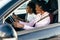 Two african young women driving using navigation on mobile phone on the road trip. Get lost