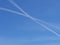 Two airplane con trails cross in the blue sky
