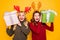 Two amazed ladies received big giftboxes for xmas wear jumpers and head horns isolated yellow background