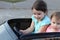 Two amazing girls ride in one big toy car on city street asphalt. Outdoor driving in a summer attraction for children