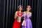 Two amazing women in santa hats and elegant evening dresses holding shopping bags