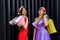 Two amazing women in santa hats and elegant evening dresses holding shopping bags