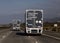 Two amazon trucks following each other driving down a freeway.