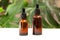 Two amber glass bottles stand on a white table against a background of monstera leaves. Natural organic eco-cosmetics. Beauty